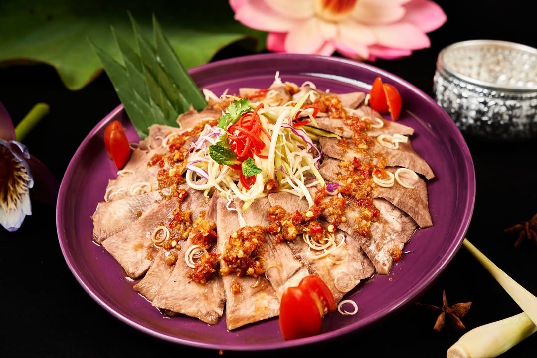 Đĩa thịt bò trộn kiểu Thái rắc lạc, rau thơm trên đĩa tím, ảnh món do VNTAY chụp